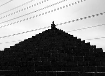 Low angle view of man standing on staircase against sky