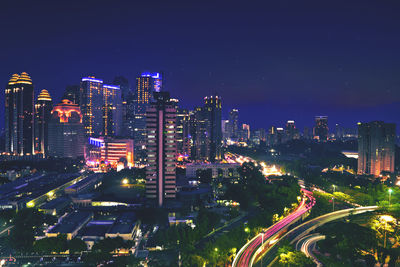 High angle view of illuminated street amidst buildings in city at night