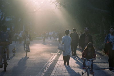 Rear view of people walking on footpath in city