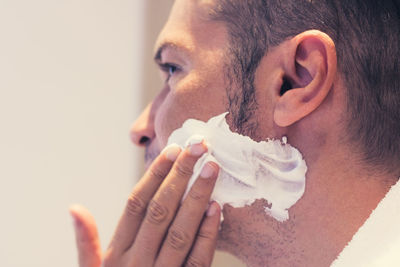 Close-up of man applying shaving cream on beard