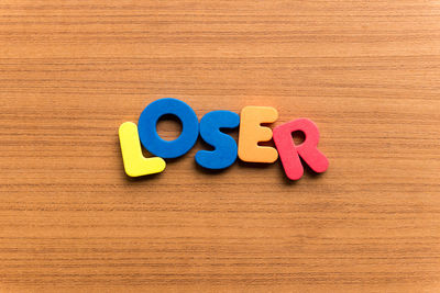 High angle view of colorful loser text on wooden table