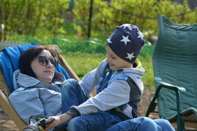 Mother with son relaxing on chair in park