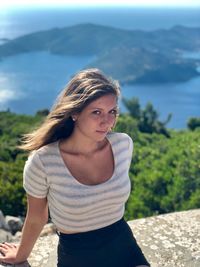 Portrait of young woman sitting against sea