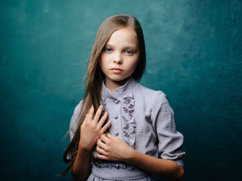 Portrait of cute girl standing against wall