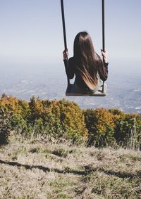 Rear view of woman sitting on swing