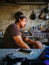 Side view of thoughtful mature man looking away while sitting in kitchen