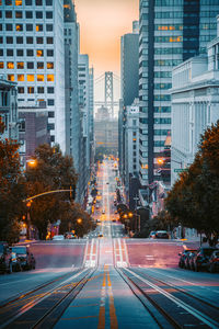 City street amidst buildings against sky at dusk