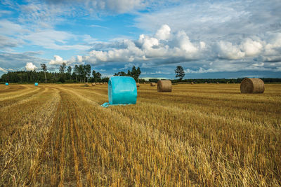 Hay bales on field against sky