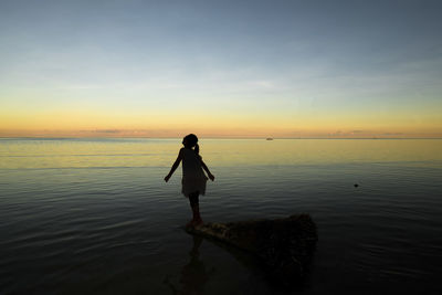 Silhouette man standing on beach against sky during sunset