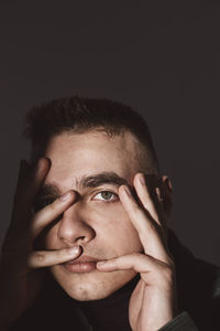 Portrait of young man touching face against wall