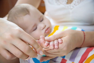 Mother cutting nails of baby at home