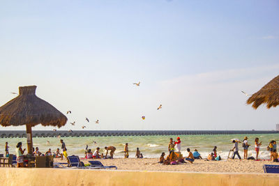 Group of people on beach against clear sky