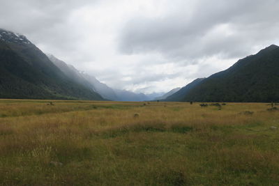 Scenic view of landscape and mountains against cloudy sky