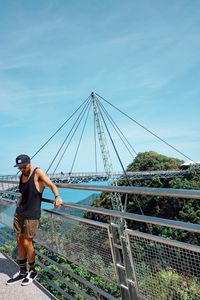 Man standing on bridge against sky