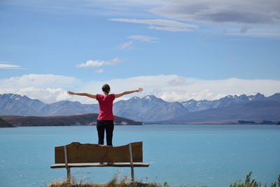 Rear view of man standing by lake against mountains