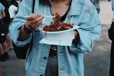 Midsection of woman having food on footpath