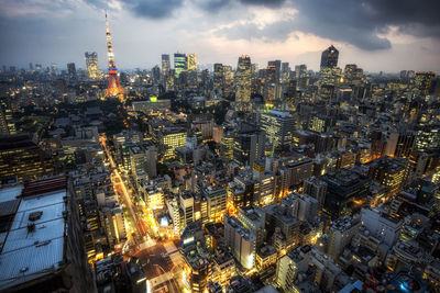 Aerial view of city lit up against cloudy sky