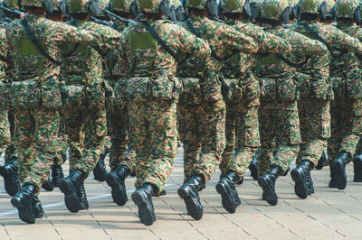 Rear view of army soldiers marching on footpath