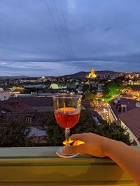 Midsection of wine glass against sky in city