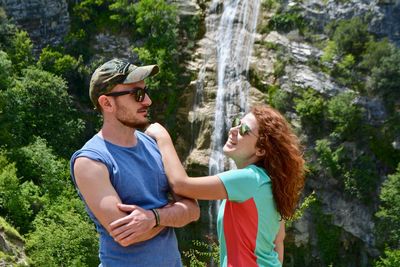 Side view of a young woman and man standing against plants