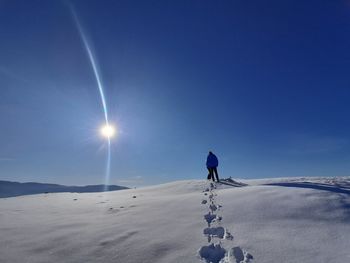 Man on snow covered land against sky