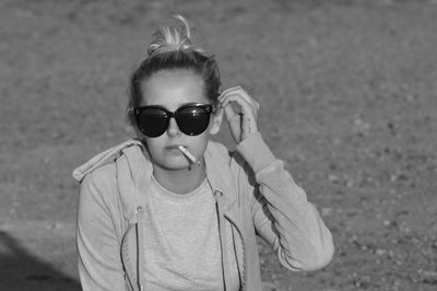 Portrait of woman in sunglasses smoking cigarette outdoors