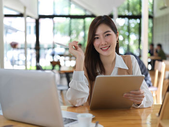 Portrait of smiling businesswoman using laptop sitting at cafe