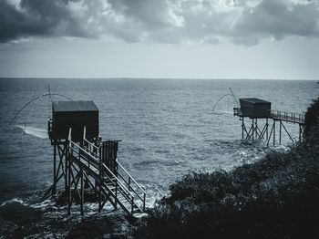 Stilt houses by sea against sky