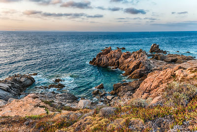 Rock formations on shore against sky