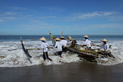 People with boat in sea against sky