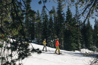 Two young women snowshoe on mt. hood on a sunny day.