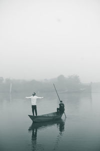 Rear view of man standing on lake in foggy weather