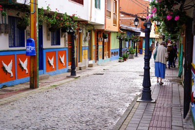 Rear view of woman walking on sidewalk in city