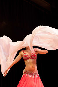 Midsection of woman standing against black background