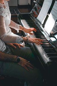 Midsection of people playing piano at home