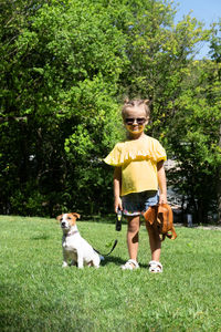 Rear view of boy with dog on grassy field