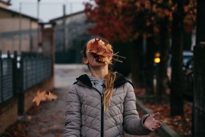 Teenage girl with autumn leaves on face at footpath