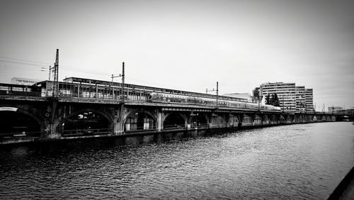 Bridge over river in city against clear sky