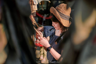 Midsection of woman holding hat standing outdoors