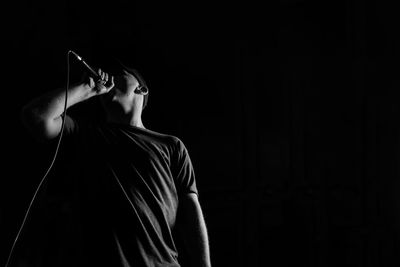 Side view of man standing against black background