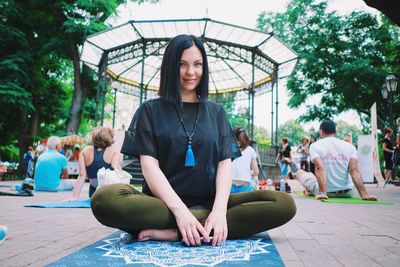 Portrait of smiling young woman sitting in park