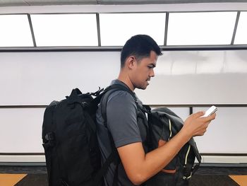 Side view of young man standing against wall