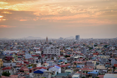 High angle view of city against cloudy sky during sunset