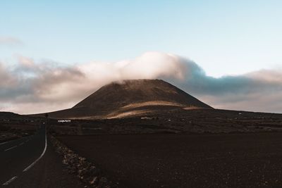 Road by mountain against sky