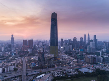 Modern buildings in city against sky during sunset