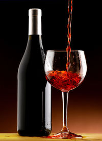 Glass of wine bottles against black background