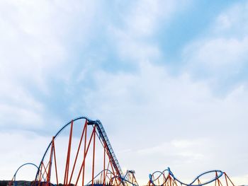 Low angle view of rollercoaster against cloudy sky