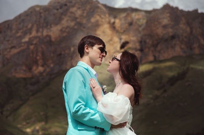 Side view of young woman standing against mountain