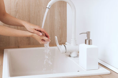 Cropped hand washing hands in bathroom