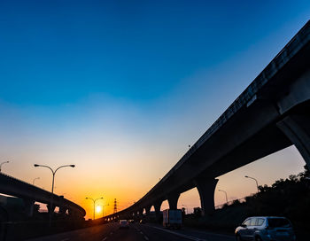 Cars on road against sky during sunset